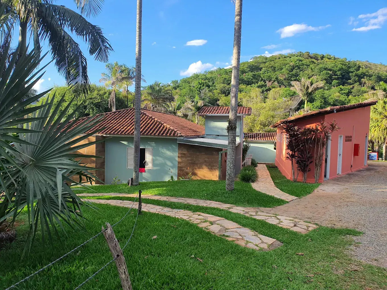 Casas da pousada entre gramados, caminhos de pedra e palmeiras